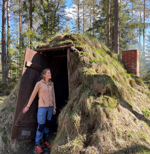 Julia Brink visar kolarkojan hon byggde med sin man förra sommaren. Jord och gräs på taket, och barkborrevirke på insidan.