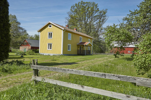 Mangårdsbyggnaden på Gudarsmåla lyser gul i sommarsolen.