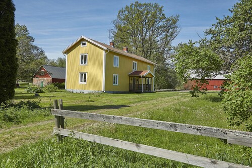 Mangårdsbyggnaden på Gudarsmåla lyser gul i sommarsolen.