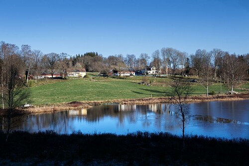 Lillasjö speglar sig vackert i landskapet. Till höger ligger gården Arvidstorp där Frida och Johans föräldrar bor.