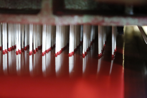 Splinten transporteras till fabriken i Tidaholm. I en så kallad komplettmaskin laddas splinten i magasin som stöter in splinten i en vandrande matta. När mattan roterar doppas splinten i paraffin och satsmassa.