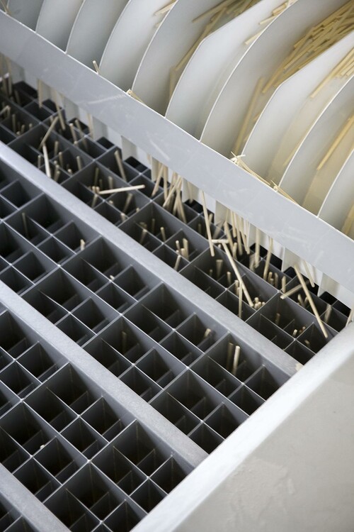 Aspkubbarna svarvas till fanér. Faneret går vidare till en stickhack som skär det till splint. Splinten sållas över perforerade aluminiumplåtar som sorterar bort defekt splint.