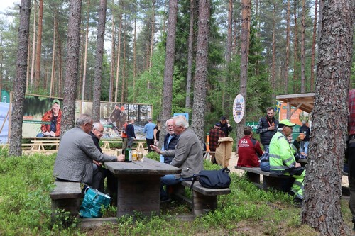 En grupp med män fikar runt ett bord i skogen